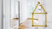 Ein zu einem Haus geformter Zollstock, hängt an einer geöffneten Tür, durch die man in eine Altbauwohnung blickt. © fotolia.com Foto: Friedberg