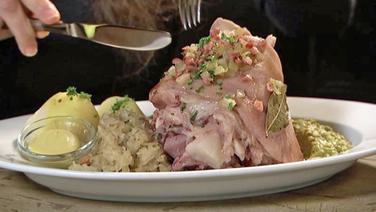 Eisbein mit Schinkenstippe, Kartoffeln, Sauerkraut und Erbsenpüree auf einem Teller serviert. © NDR 