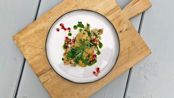 Rotbarsch mit Blumenkohl-Taboulé und Pesto auf einem Teller serviert. © NDR 