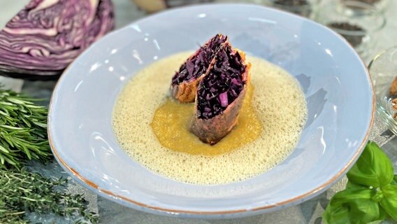 Rotkohl-Röllchen mit Gewürzpolenta und Buttersoße auf einem Teller serviert. © NDR Foto: Florian Kruck