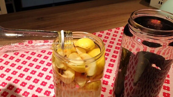 Alkohol wird in Gläser mit Obst gegossen für die Zubereitung eines Schlehenlikörs. © Ria Springhorn 