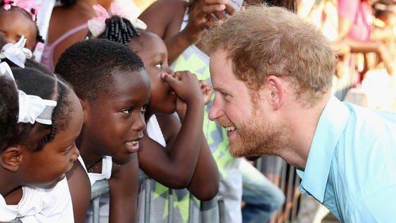 Prinz Harry begrüßt Kinder bei einem Straßenfestival auf der Karibik-Insel St. Lucia. © picture alliance / empics Foto: Chris Jackson