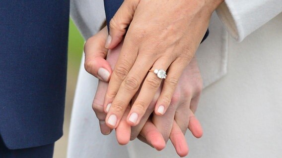 Die Hand des britischen Prinz Harry (l) und die Hand der US-amerikanischen Schauspielerin Meghan Markle mit Verlobungsring, aufgenommen am 27.11.2017 in London (Großbritannien) nach Bekanntgabe der Verlobung. © dpa Bildfunk Foto: Dominic Lipinski/PA/AP/dpa