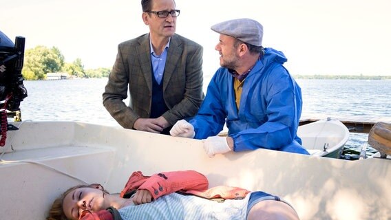 Kriminaldirektor Lars Englen (Ingo Naujoks, l.) und der Pathologe Dr. Henning Strahl (Christoph Tomanek, r.) finden in einem Boot den leblosen Körper der 21-jährigen Sofie Albers (Johanna Ingelfinger). © NDR/ARD/Georges Pauly 