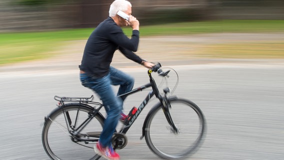 Ein Radfahrer telefoniert mit seinem Handy beim Fahren auf einer Straße. © picture alliance / dpa Foto: Patrick Pleul