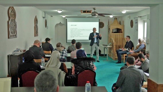 Ein Dozent steht vor den Kollegiaten des Islamkolleg in einer Moschee. © NDR 