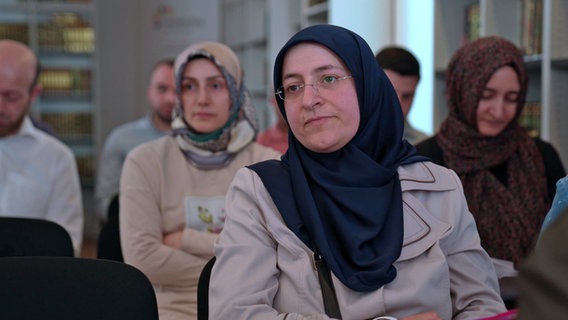 Elif Demirkan-Çoban sitzt zwischen anderen Kollegiatinnen des Islamkolleg Osnabrück im Unterricht. © NDR 