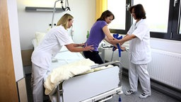 Zwei Krankenschwestern stützen eine Patientin auf Krücken ©  imago/Jochen Tack 