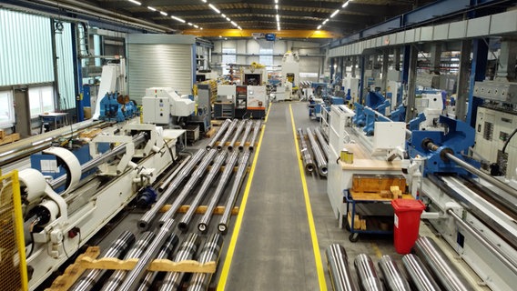 Blick in eine langgestreckte Werkshalle mit Geräten und am Boden lagernden Kanonen. © NDR/Klaus Scherer 