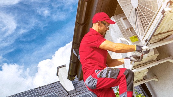 Monteur auf einer Leiter installiert die Außeneinheit einer Wärmepumpen-Anlage an der Hausmauer. © Colourbox.de |Tomasz Zajda/Virrage Images Inc Foto: Tomasz Zajda