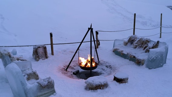 Eine Sofa aus Eis im Schnee vor einer Feuerschale. © NDR/Gitta Meding 