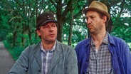 Szenenbild aus der 10. Büttenwarder-Folge "Schuld und Sühne": Brakelmann und Adsche latschen einen Feldweg entlang. © NDR 