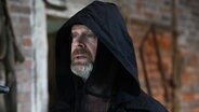 Ein Mann mit schwarzem Umhang. Matthias Matschke in der Rolle des Tods in der 92. Büttenwarder-Folge "Der Tod ist ein sturer Arsch". © NDR/Nico Maack 