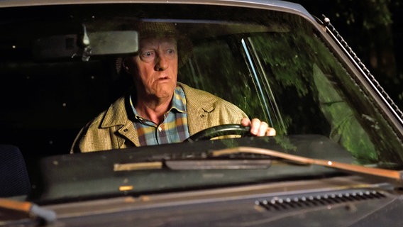 Szenenbild aus der 75. Büttenwarder-Folge "Nachruhm": Shorty sitzt in der Dunkelheit am Steuer seines Wagens. © NDR/Nicolas Maack Foto: Nicolas Maack
