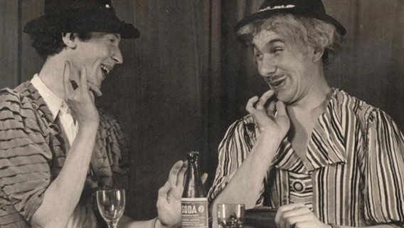 Günter Kütemeyer und eine andere Person in einem alten Theaterstück. Beide sitzen am Tisch. © NDR 