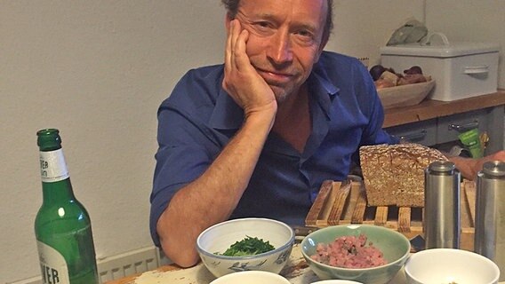Kuno - Sven Walser - sitzt am Küchentisch vor den Zutaten für Matjestartar. © NDR 