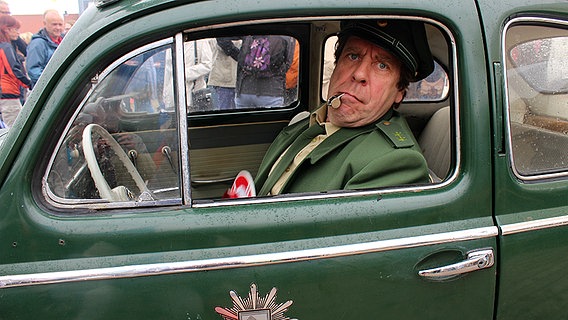 Dorfpolizist Peter (Uwe Rohde) in einem Polizeiauto © NDR Foto: Nicola Millies