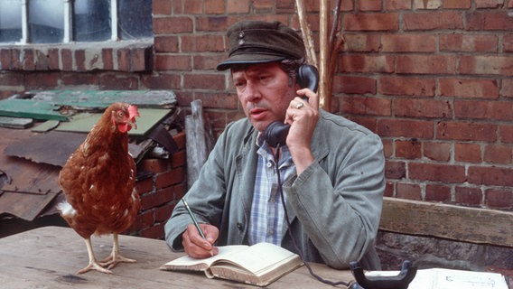 Szenenbild aus der 10. Büttenwarder-Folge "Schuld und Sühne": Brakelmann sitzt vor seinem Bauernhaus und telefoniert. © NDR/Nico Maack 
