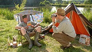 Szenenbild aus der 26. Büttenwarder-Folge "Endlich Urlaub": Brakelmann und Adsche zelten am See. © NDR/Nico Maack Foto: Nico Maack