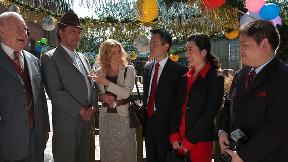 Szenenbild aus der 13. Büttenwarder-Folge "Staatsbesuch": Schönbiehl und Brakelmann empfangen die chinesischen Delegation. © NDR/Nico Maack 