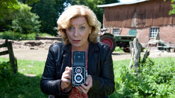 Szenenbild aus der 36. Büttenwarder-Folge "Nackt": Fotografin Eleonore Schaubenheimer hat eine Kamera in der Hand. © NDR/Nicolas Maack 