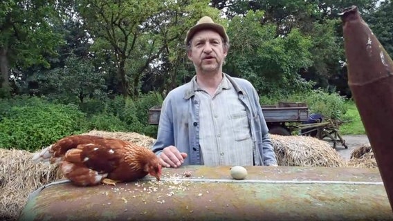 Adsche steht am Trecker, darauf liegt ein Huhn und ein Ei. © NDR 
