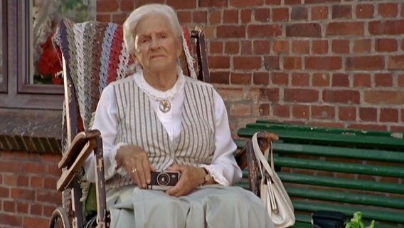 Szenenbild aus der 35. Büttenwarder-Folge "Ostern": Hermine Harksen sitzt vor dem Dorfkrug. © NDR 