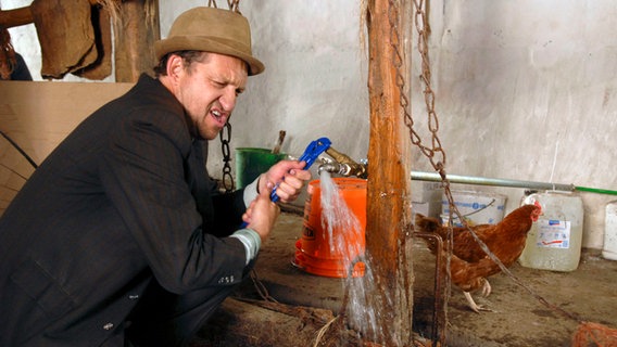 Adsche versucht den Wasserhahn zu reparieren. © NDR/Nicolas Maack Foto: Nicolas Maack