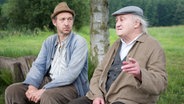 Szenenbild aus der 53. Büttenwarder-Folge "Sinn": Adsche und Onkel Krischan sitzen am Dorfteich. © NDR/Nico Maack Foto: Nico Maack