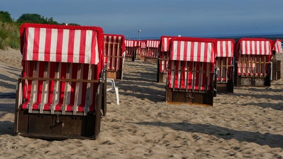 Am frühen Morgen sind die rot-weißen Ostseestrandkörbe in Koserow auf der Insel Usedom noch leer, in der Urlaubszeit füllen sie sich aber ganz bald. © NDR Foto: Achim Otto aus Wöbbelin