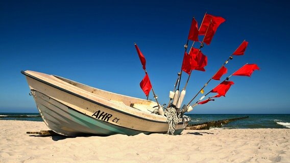 Ein Fischerboot mit roten Fahnen liegt am Strand. © NDR Foto: Katrin Schäfer aus Blankenhagen