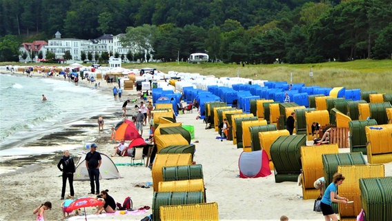 Am Strand stehen bunte Strändkörbe und Menschen gehen baden. © NDR Foto: Wolfgang Fischer aus Fintel