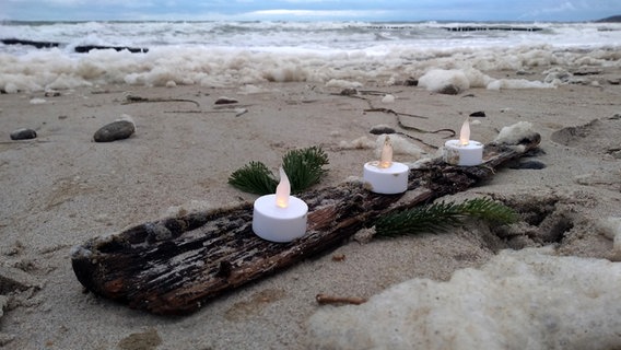 Kerzen auf Treibgut am Strand. © NDR Foto: Jana Hobe aus Rostock