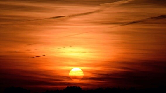 Der helle Sonnenball schimmert hinter rot gefärbten Wolken hervor. © NDR Foto: Katrin Schäfer aus Blankenhagen