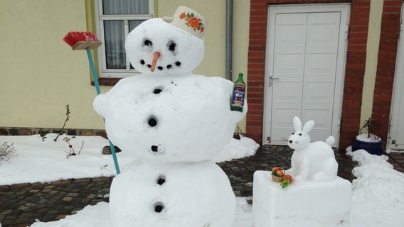 Ein Schneemann und ein Schneehase stehen vor einem Haus. © NDR Foto: Hannes Ruß aus Rethwisch