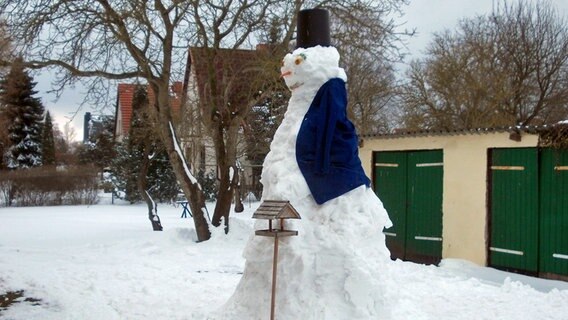 Ein übermannsgroßer Schneemann steht vor einem Garagenkomplex. © NDR Foto: Andreas Nahbein aus Bentwisch