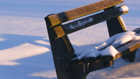 Eine verschneite Bank im Sonnenschein. © NDR Foto: Andreas Erdt aus Dummerstorf