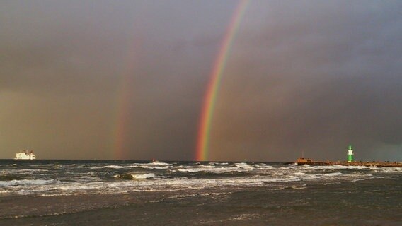 Regenbogen steigt aus der Ostsee über den grünen Leuchtturm von Warnemünde © NDR Foto: Monika Laaser aus Rostock