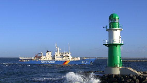 Schiff der Küstenwache fährt vorbei am grünen Leuchtturm in Warnemünder Hafen. © NDR Foto: Danilo Schubert aus Rostock