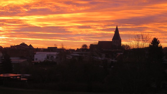 Sonnenaufgang mit einer Stadt im Vordergrund © NDR Foto: Egon Goschow aus Gnoien