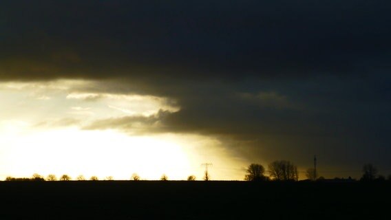Sonne blitzt durch dunkle Wolken über einem Feld. © NDR Foto: Gunther Draheim aus Rostock