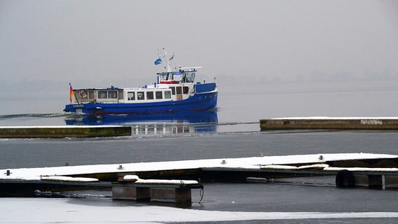 Eine blau weiße Barkasse fährt vom Anleger ab Richtung offene See. © NDR Foto: Werner Bayer aus Neubrandenburg