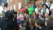 Eine Kamera filmt Menschen, die auf einer Treppe setehn bei der Übergabe eines Ballons, in dem die Stadtwette enthalten ist. © ndr.de Foto: Johann Lühe