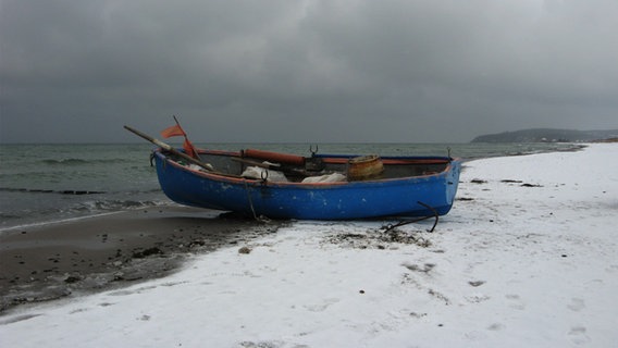 Ein Fischerboot liegt an einem verschneiten Strand. © NDR Foto: Christine Arendt aus Kloster/Hiddensee
