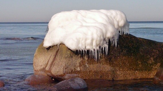 Ein Felsen im Wasser trägt eine dicke Schneehaube mit Eiszapfen © NDR Foto: Volker Neumann aus Schleswig