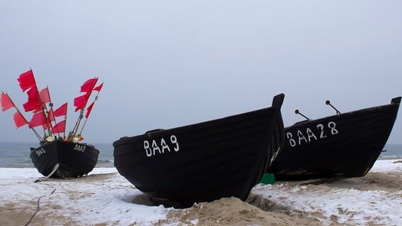 Drei Schiffe aus Holz  liegen am Strand. Das Schiff auf der linken Seite ist mit roten Fahnen bestückt. © NDR Foto: Dirk Auerbach aus Stralsund
