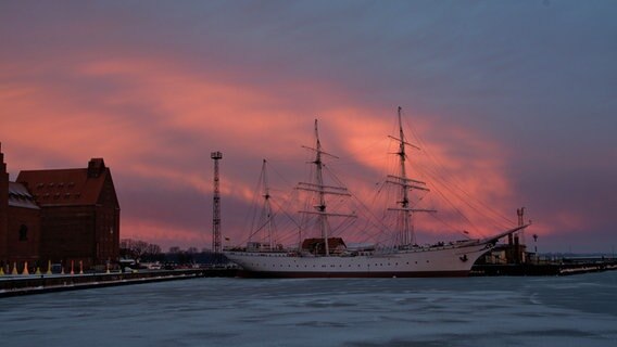 Ein großes Segelschiff steht bei Sonnenaufgang im Hafen. © NDR Foto: Manfred Sagan aus Stralsund