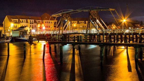 Eine Zugbrücke bei nächtlicher Beleuchtung über einem gefrorenen Gewässer. © NDR Foto:  Uwe Kranzt aus Hinrichshagen