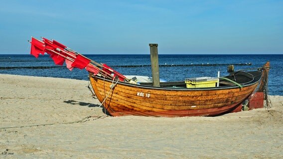 Ein kleines Fischerboot mit roten Fahnen liegt am Strand. © NDR Foto: Norbert Brandt aus Neubrandenburg