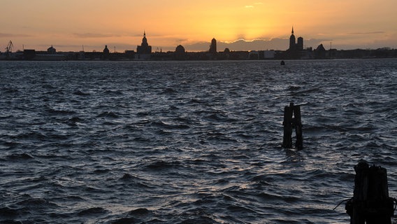 Blick vom Wasser aus auf eine Stadtsilhouette mit Sonnenuntergang © NDR Foto: Anne Schönemann aus Stralsund